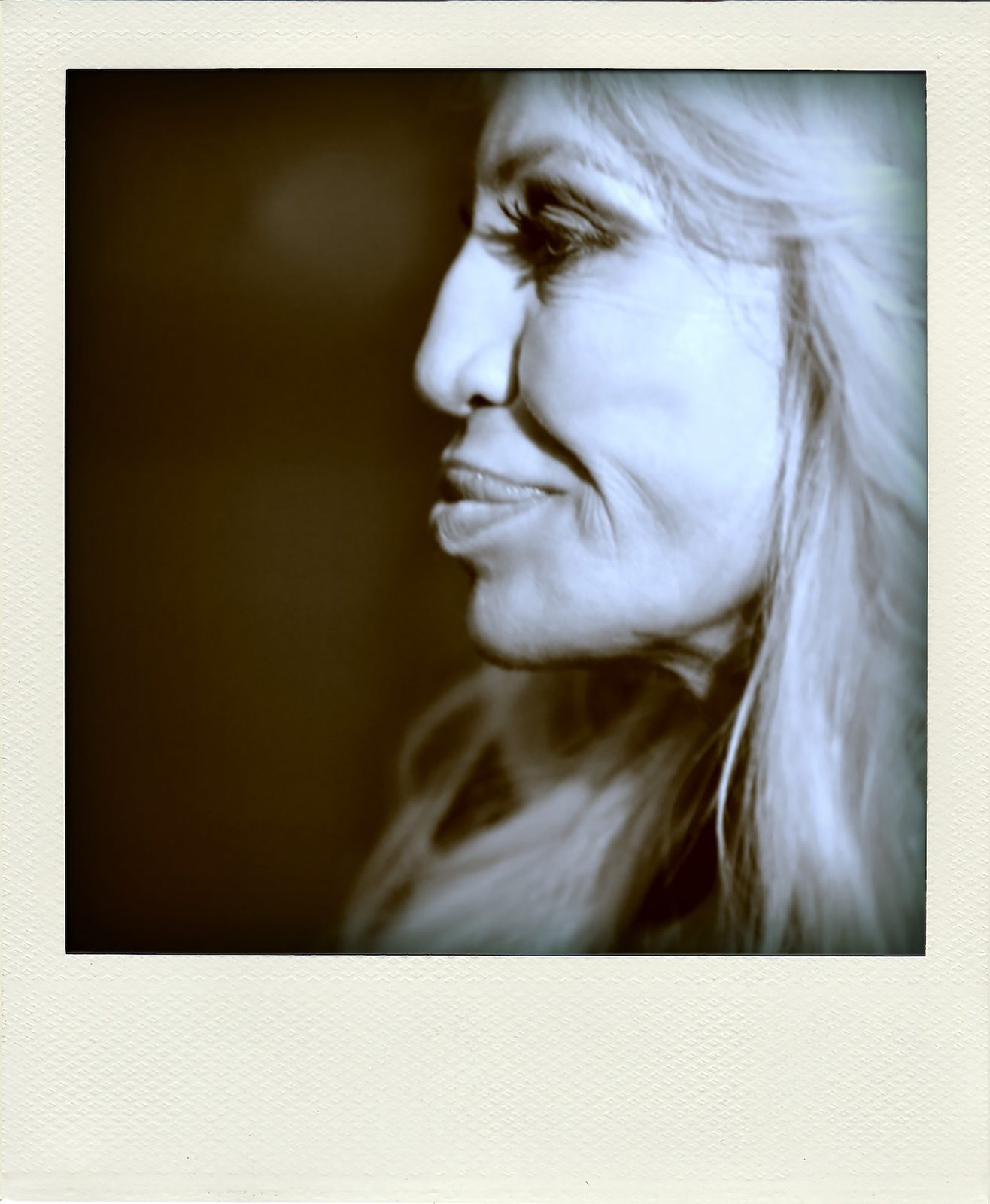 Polaroid backstage portrait of Donatella Versace in profile, capturing her distinctive silhouette in a candid moment at Milano Fashion Week. Donatella Versace by Tony Federico, Woman Portrait Gallery.